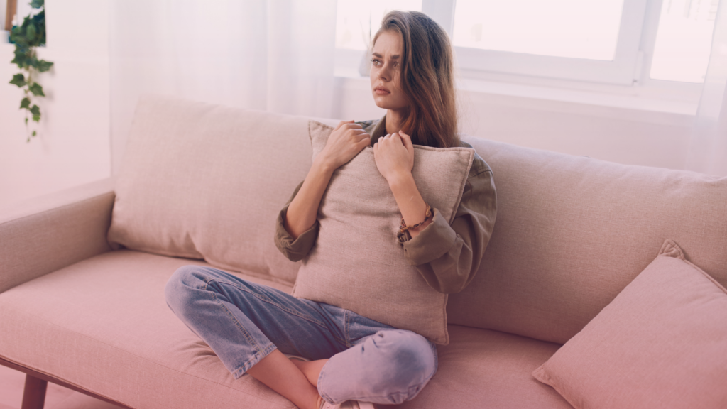 A woman sitting on a sofa feeling anxious about an upcoming MIAM appointment.