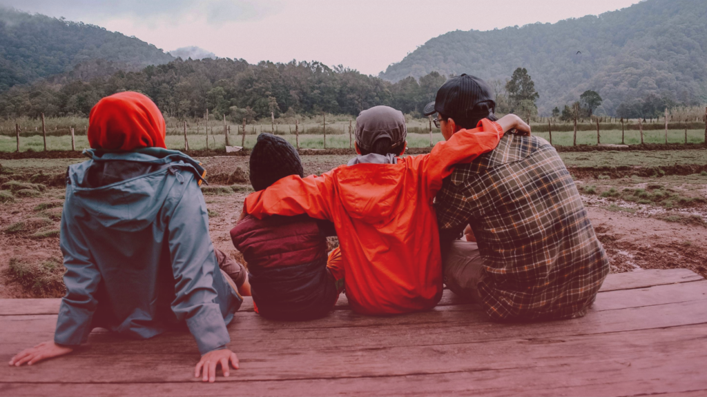 A family sitting apart on a wooden path, reflecting the breakdown of child arrangements.
